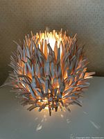 Front view of lamp illuminated showing wooden twig shade design and glow