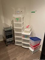 Full view of 3 organizing towers and 4 plastic storage containers stacked next to them in corner.