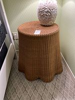 Full view of round wicker side table with scalloped base showing overall shape and size.