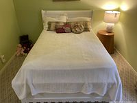 Full front view of assembled bed frame with mattress, box spring, cushions