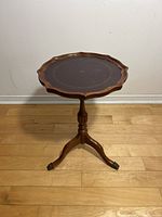 Full view of vintage wooden side table showing tripod base and round scalloped top.
