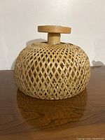 Front view of the woven bamboo ceiling pendant light showing the basket-like rounded shade and wooden mounting piece.