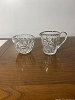 Pair of vintage cut glass creamer and sugar bowl side by side showing full shape and design.
