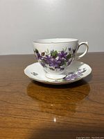 Side view of the bone china cup and saucer featuring purple violets pattern and gold trim