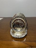 Front view of silver-plated coasters in holder showing grapevine pattern and shiny finish.