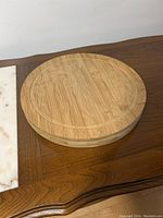 Round bamboo cheese board on wooden table with natural finish, 11.5 inches in diameter.