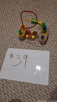 Front and side view of wooden abacus bead maze on carpet with a white board showing #39.