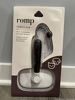 Front side of original packaging showing Romp Vanity Fur branding, black handle slicker brush visible inside clear plastic blister pack.