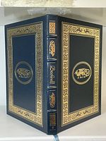 Full view of the front and spine of the leather bound book showing gilt decorations and title Beowulf