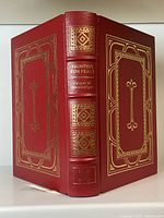 Front and spine view of the red leather-bound book with gilt decorations titled Fighting for Peace by Caspar W. Weinberger.