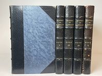 Front view of the five volumes showing half-leather bindings with blue covers and black leather corners.