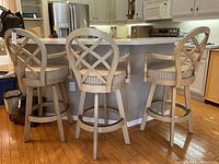 Three matching high top swivel bar stools arranged at a kitchen counter, showing front and back views with wooden lattice backs and striped seats.