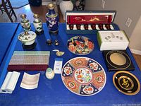 Full assortment of Asian decor on blue table including vases, plates, lidded containers, and sake set.