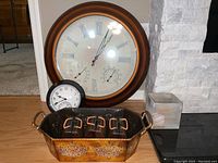Photo showing large round wall clock, small tabletop clock, and metal decorative container with six small glass jars inside.