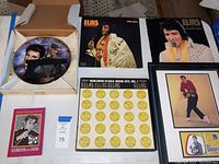 Photo of the full collection arranged on table showing collector plate, vinyl records, framed wall art, framed award display and book.