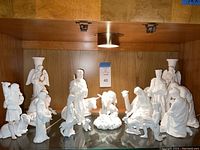 Full display of the nativity set featuring central nativity figures and animals arranged in a cohesive scene within a wooden cabinet shelf.