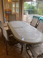 Outdoor oval stone top table from angle showing textured surface and central hole for umbrella.