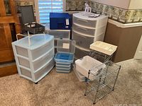 Full view of assorted storage and organization items on carpeted floor including plastic drawers, wire shelves, storage bins and organizers.