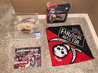 Full view of the limited edition Tampa Bay Buccaneers medallion football in protective case, leather key ring, scarf, 2020 champions book, and Chicago Bears reversible furniture protector.