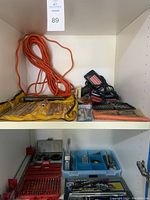 View of the orange extension cord, multiple screwdriver bit sets, and some miscellaneous tools in plastic cases and organizers.