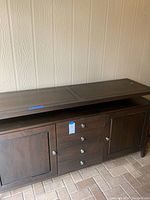 Front view of a dark wooden TV stand with closed drawers and cabinet doors.