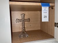Crystal cross standing in wooden cabinet, showing front and side profile.