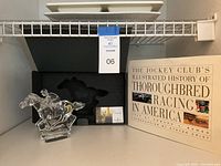 View of the Waterford crystal horse and jockey figurine displayed alongside its original box and the Jockey Club book.