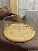 Front view of clear glass souffleform serving bowl seated on cork base, showing the bowl's top opening and thickness of cork base.