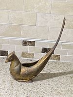 Front and side view of the Japanese gold gilt abstract bird incense burner, placed on kitchen counter with tile backsplash.