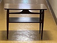 Front view of the MCM end table showing faux wood grain Formica top, middle shelf and tapered wooden legs with SA line design