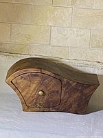 Side view of Tasmanian Myrtle Burl wooden jewelry box with curved design and one drawer closed.