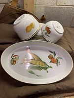 Top view of three bowls placed upside down and oval platter showing corn and fruit design