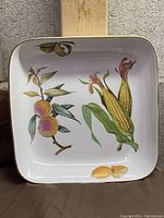 Top-down photo of the square porcelain server showing the colorful fruit and vegetable Evesham design with peaches, corn cobs, and lemon slices.