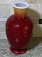 Front view of a vintage Avon Spring Bouquet Oriental Red scented vase showing embossed floral design with gradient red to yellow glaze.