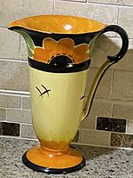 Side view of vintage Art Deco Myott Son Co ceramic serving jug, showing large orange flower design and curved handle.