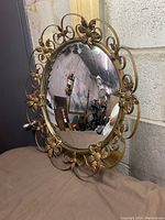 Front view showing the round fisheye convex bubble dome glass mirror with decorative gold-tone flower and butterfly metal frame hanging on the wall.