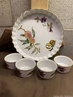 Front view of one round server plate with Evesham design and four matching small bowls arranged in front