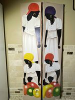 Photo showing two vertical fabric paintings side by side depicting Black women in white dresses with colorful headscarves, carrying market fruit baskets.