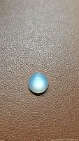 Clear close-up of round pearl white moonstone showing surface texture and light reflection.