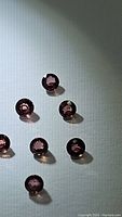 Eight round pink sapphires on a white surface related to a certified exotic sapphire lot.