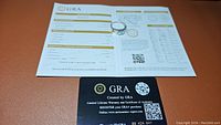 Ring atop a grading report proving the moissanite certification by GRA, showing authenticity and grading details.