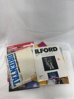 Photo showing a stack of assorted open packages of photo papers from different brands including Canon, Ilford and Oriental