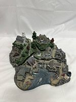 Front angle of the entire Fisherman’s Cove set showing miniature buildings, boats, lighthouse, and trees on a base painted to resemble water and rocks.