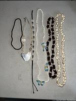 All six necklaces laid flat showing styles and materials including shells, beads, cords, and a mother-of-pearl pendant.