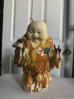 Front view of the porcelain figurine showing child figure with animal ears holding a lotus pod, and a deer figure beside.