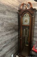 Full view of tall wooden Sligh grandfather clock against wall