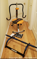 Photo showing the twist exercise machine with orange and black padding and the pull-up bar placed on the floor with exercise DVD and book.
