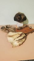 Four fur hats displayed on a surface, including a small brown fur hat and other varied styles.