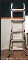 Full view of aluminum multi-function folding ladder in folded position showing blue lock handles and aluminum rungs.