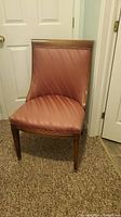 Front view of pink upholstered chair with wood frame, showing seat and backrest.